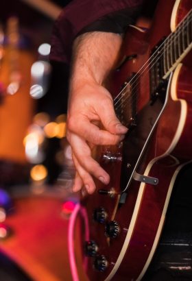 person's hand playing guitar